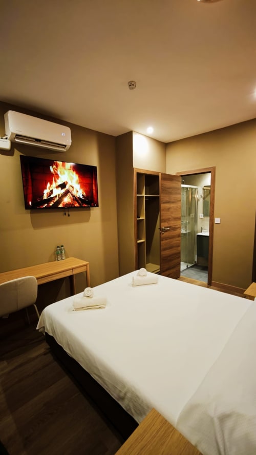 Habitación doble premium del Hotel Continental Calella con chimenea, TV, cama blanca, escritorio de madera, aire acondicionado y baño privado