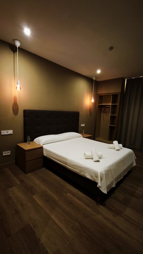 Habitación doble Premium del Hotel Continental Calella con decoración moderna, ropa de cama blanca, cabecero oscuro, iluminación colgante y