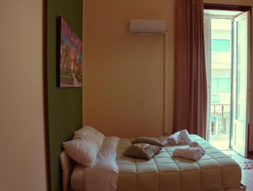 Luminosa camera tripla presso Mizzica Rooms a Palermo con biancheria bianca, balcone con vista sulla città, aria condizionata e moderno