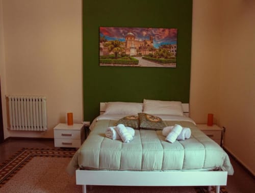 Camera tripla Mizzica Rooms Palermo con letto queen, parete accent verde e quadri con veduta città