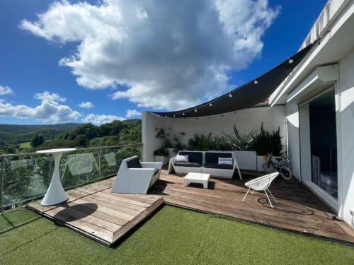 Terrasse de villa moderne à la Résidence Thalie avec terrasse en bois, mobilier contemporain, voile d'ombrage noir et vue sur la vallée verdoyante
