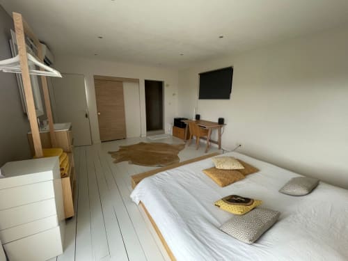 Chambre élégante de villa moderne aux draps blancs, mobilier en bois, télévision et bureau du gîte Les Trois-Îlets avec vue mer