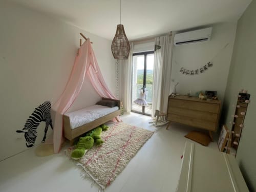 Chambre d'enfant lumineuse à la villa Les Trois-Îlets avec lit à baldaquin rose, mobilier en bois et accès à la terrasse vue mer