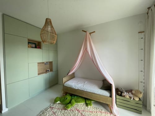 Chambre d'enfant avec lit en bois, baldaquin rose, rangements verts, lampe suspendue tressée et siège confortable vert aux Trois-Îlets