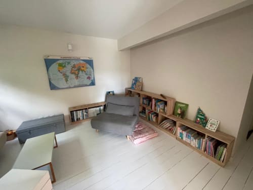Séjour moderne à la Résidence Thalie avec canapé, bibliothèques en bois, sol blanc et carte du monde murale