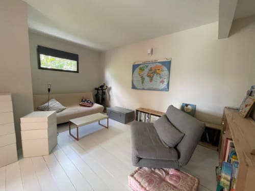 Chambre moderne de la villa Les Trois-Îlets avec lit, canapé, mappemonde, bibliothèque et vue sur la mer