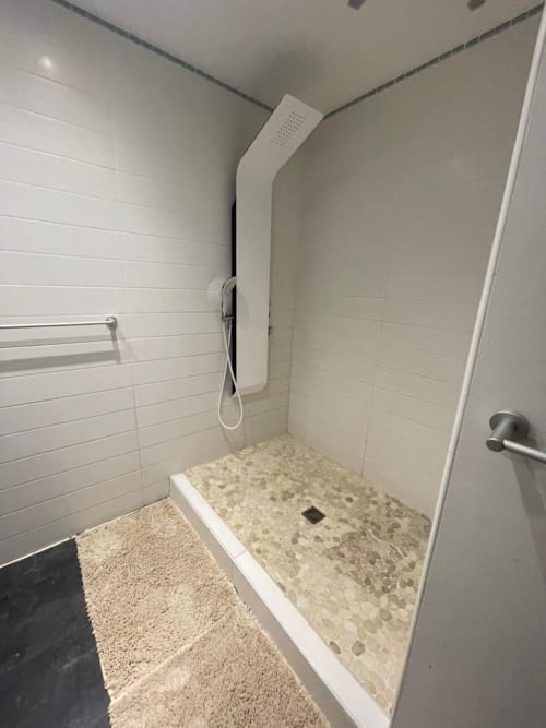 Douche extérieure moderne aux murs carrelés blancs et sol en galets à la villa Résidence Thalie aux Trois-Îlets