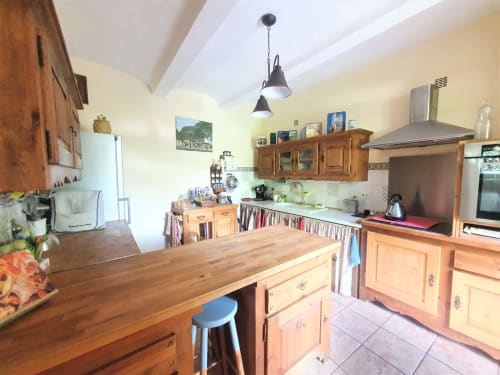 Spacious kitchen in French Cévennes gîte with wooden cabinets, island counter, stainless steel appliances, and bright yellow