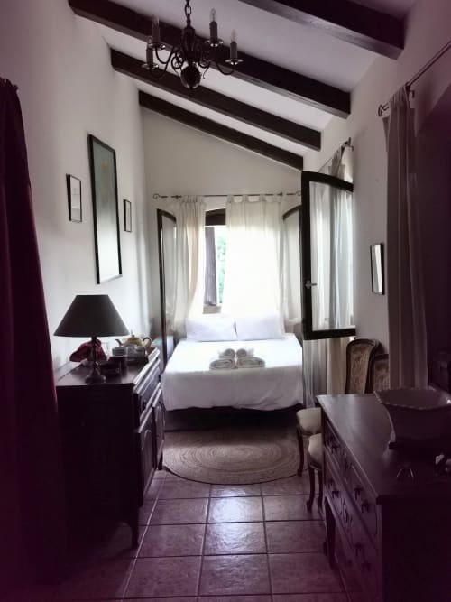 Elegant bedroom with four-poster bed, dark wood furniture, and mountain views at Mes Maisons gîtes in Cévennes, France.