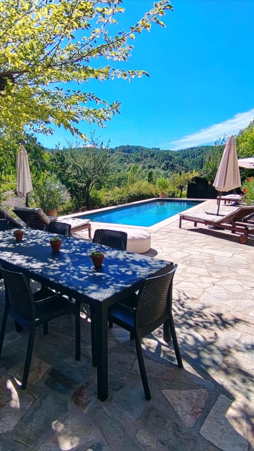 Luxury poolside dining area at Mes Maisons gîtes in the Cévennes with mountain views, private pool, and outdoor furniture.