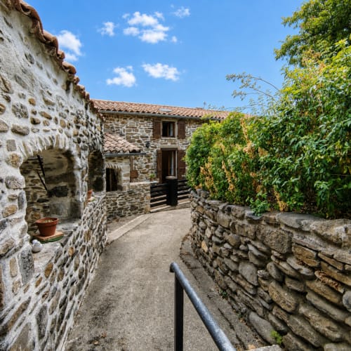 Stone cottage gîte courtyard with ivy-covered walls and mountain views in Cévennes, France