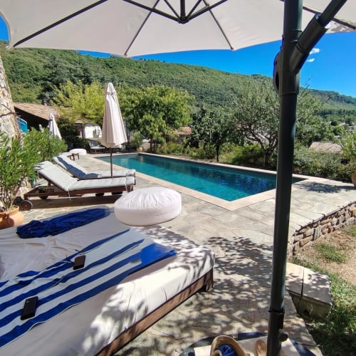 Luxury pool terrace with loungers and umbrellas overlooking Cévennes mountains, South of France