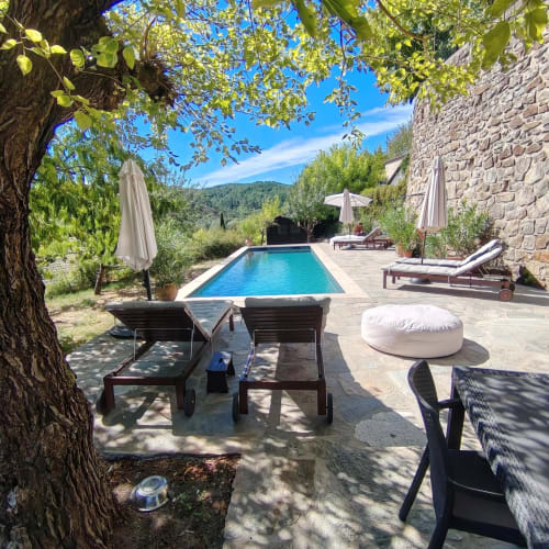 Luxury French villa pool with loungers under ancient tree, stone building, mountain views, Cévennes