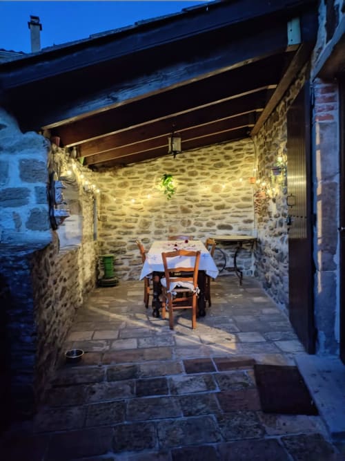 Outdoor dining patio at Mes Maisons gîte in Gagnières, France, with stone walls and candlelit table under pergola