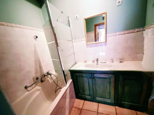 Bathroom with pink tiles, white sink, dark vanity, bathtub with shower, and green walls at French gîte
