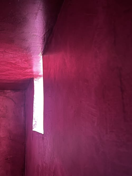 Couloir illuminé de magenta à l'hôtel boutique Clos Bb à Saint-Cyr sur Mer, France, montrant un éclairage ambiant moderne par la porte