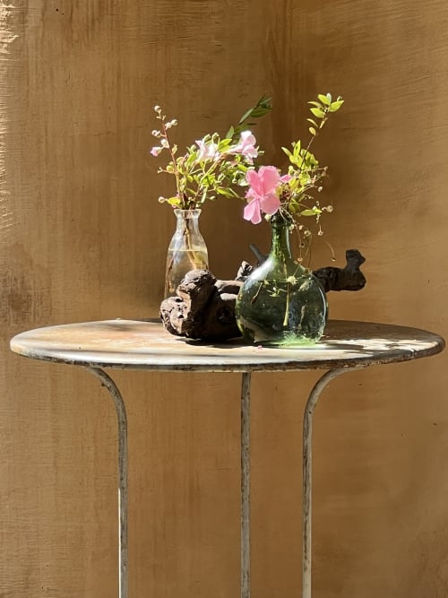 Table ronde rustique en marbre avec des fleurs roses dans des vases en verre au Clos Bb, Saint-Cyr-sur-Mer