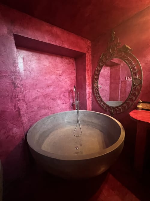 Salle de bain spa luxueuse au Clos Bb à Saint-Cyr sur Mer avec murs bordeaux, baignoire circulaire en pierre et miroir orné