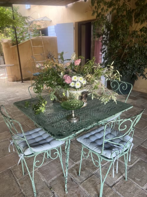 Charmant patio du Clos Bb à Saint-Cyr sur Mer, avec mobilier vintage en métal vert et arrangements floraux frais