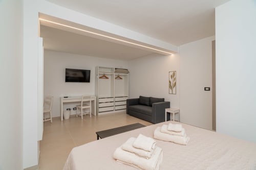 Modern studio apartment at Short Let's Olbia featuring bed, sofa, desk, wardrobe and flat-screen TV