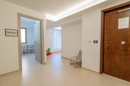 Modern hallway at Short Let's Olbia with kitchen access, wooden door, and comfortable seating in Olbia