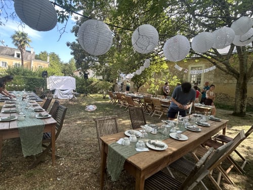 Réception en jardin à la Cour Du Liège à Baugé-en-Anjou avec tables en bois, couverts, lanternes et blanc
