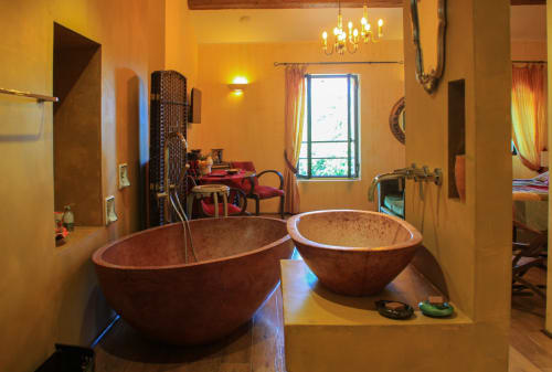 Salle de bains luxueuse au Clos Bb avec deux baignoires rondes en terre cuite, murs jaunes, lustre et fenêtre donnant sur Saint-Cyr sur
