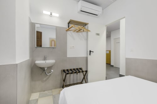Moderna habitación doble con baño ensuite en el hotel Pensión Castil de Granada, con paredes blancas y suelo de azulejos