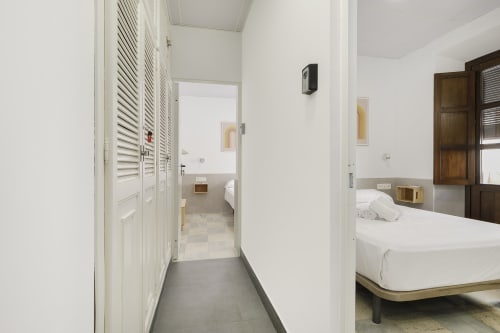 Pasillo moderno del hotel Pensión Castil Granada con dormitorio, paredes blancas, piso oscuro y acceso a baño compartido
