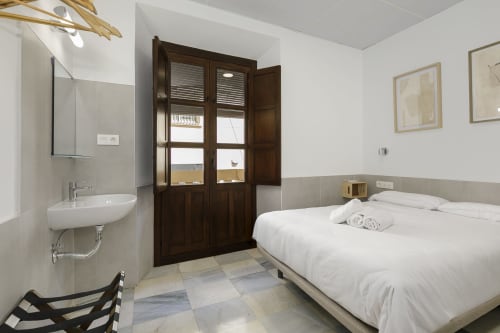 Dormitorio doble con baño compartido en Pensión Castil Granada, con cama blanca y puertas de madera oscura