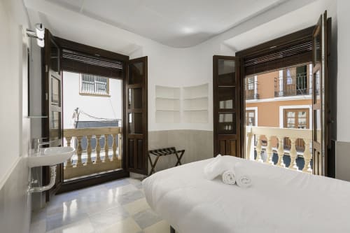 Habitación doble con vistas a la ciudad y baño compartido en Pensión Castil, Granada, con puertas de balcón y suelos de azulejos