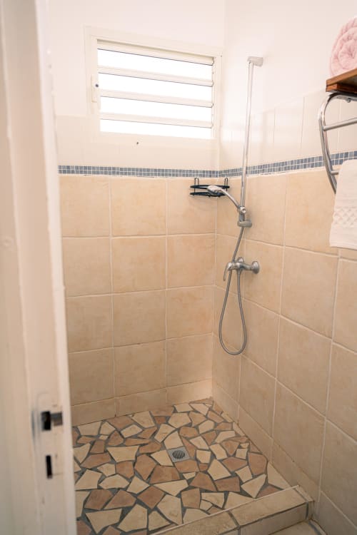 Douche moderne au sol en carrelage géométrique et murs en carreaux beige au gîte Le Nid De Bellemont à Trois-Rivières