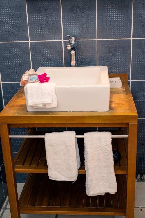Vasque blanche moderne, dosseret en carrelage bleu foncé et meuble-lavabo en bois au Nid De Bellemont