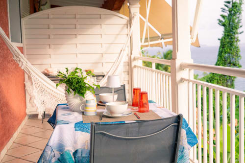 Coin repas sur la terrasse du gîte Le Nid De Bellemont avec vue mer, plantes en pot et balustrade blanche