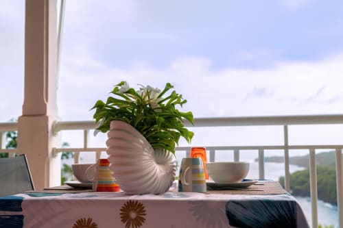 Coin repas sur balcon avec vue mer au gîte Le Nid De Bellemont à Trois-Rivières, avec plante en pot et océan en arrière-plan