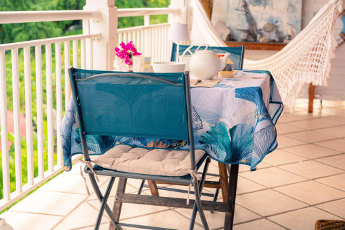 Balcon de chalet côtier au Nid De Bellemont avec chaises en maille bleue, fleurs roses et vue sur mer à Trois-Rivières,