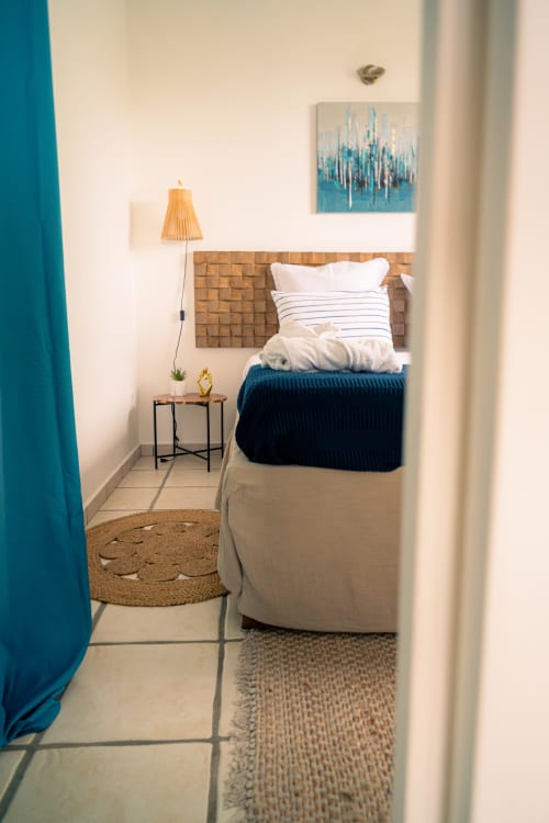 Chambre avec vue sur mer au Nid De Bellemont à Trois-Rivières avec tête de lit tissée, accents bleus et lampe en bois