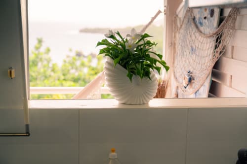 Vase blanc garni de fleurs sur le rebord de fenêtre à Le Nid De Bellemont, avec vue sur la mer à Trois-Rivières