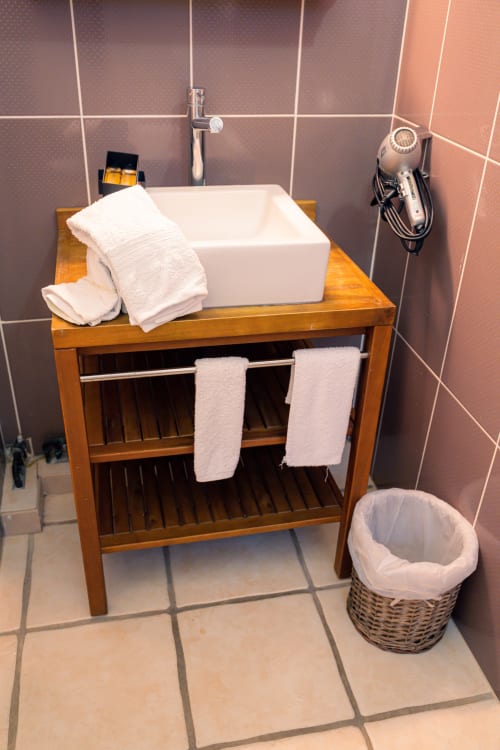 Lavabo blanc rectangulaire avec serviettes blanches et panier en osier dans le gîte Le Nid De Bellemont, Trois-Rivières