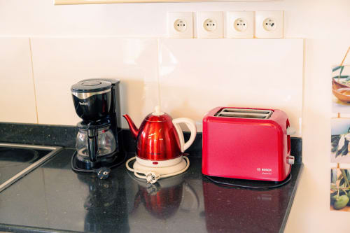 Comptoir de cuisine avec cafetière noire, bouilloire rouge et grille-pain Bosch rose au gîte Le Nid De Bellemont, Trois-Rivières