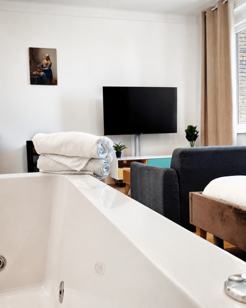 Suite jacuzzi privée à l'hôtel Nancy-Place avec baignoire spa, TV écran plat et mobilier moderne