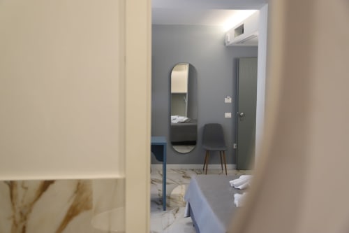 Camera moderna di Totonno's Rooms a Tropea con vista sulla città, pareti grigie, specchio ovale e accogliente zona living