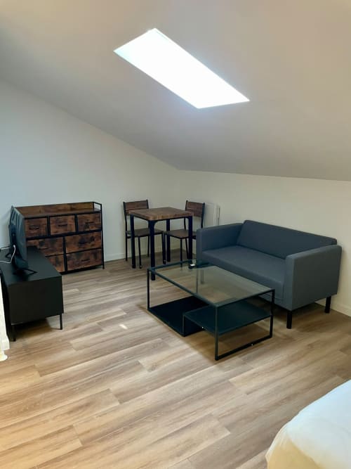 Studio spacieux à l'Hôtel d'Angleterre Vittel avec mobilier moderne, canapé gris, coin repas, commode en bois