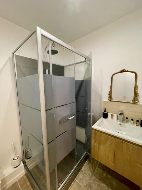 Salle de bain moderne du studio Hôtel d'Angleterre avec douche vitrée, vasque en bois et miroir décoratif