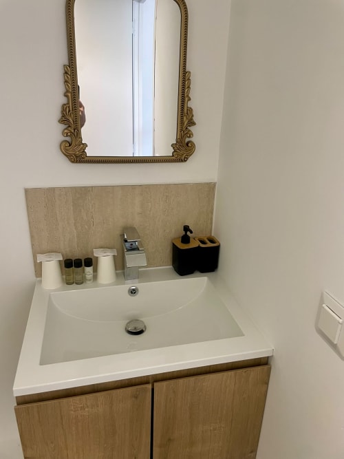 Vasque blanche, meuble en bois, dosseret en travertin et miroir ornementé à l'Hôtel d'Angleterre Vittel