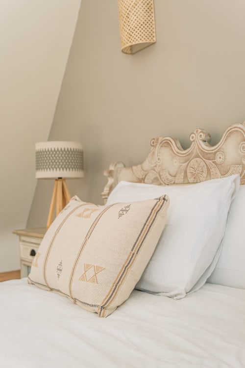 Chambre douillette à la Ferme de Kervihern avec coussins décor, tête de lit beige et lampe de table