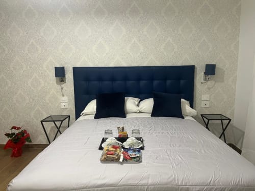Camera moderna a Maritza Guest House Roma con testata blu navy, biancheria bianca e servizi di benvenuto