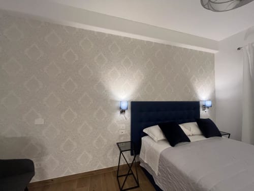 Camera moderna presso Maritza Guest House Roma con testata nera, biancheria bianca, carta da parati a motivi e design contemporaneo