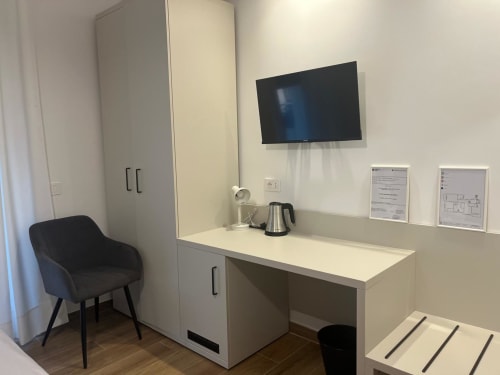 Camera moderna della Maritza Guest House a Roma con scrivania, TV a schermo piatto, bollitore e poltrona nera