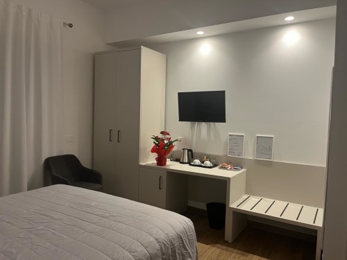 Camera moderna a Maritza Guest House a Roma con letto matrimoniale, TV a parete, angolo cottura con fiori rossi e design contemporaneo